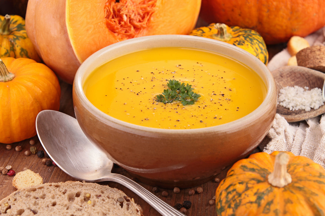 bowl of pumpkin soup on a table with squashes