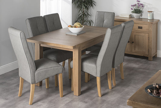 Oak dining table with six grey faux leather dining chairs and oak sideboard in the background