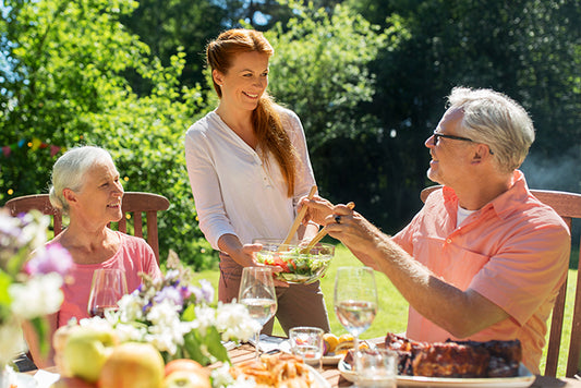 Lady serving salad to her parents at an outdoor table on a sunny day