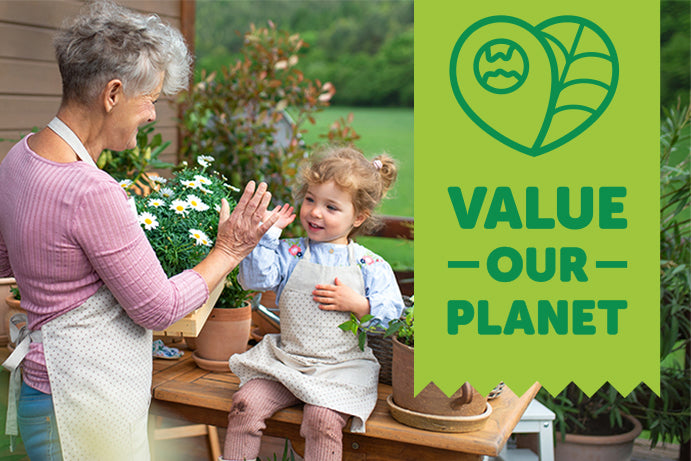 Grandmother and granddaughter high fiving in a garden with a banner saying value our planet