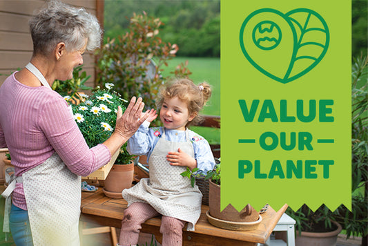 Grandmother and granddaughter high fiving in a garden with a banner saying value our planet