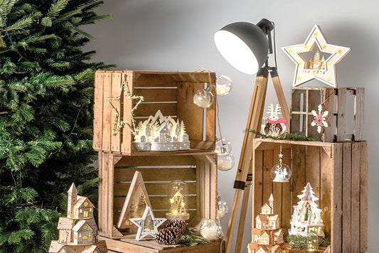 Scandi style white christmas decorations displayed on wooden crates with a lamp