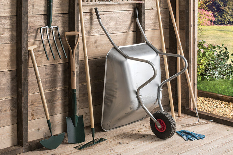 A collection of gardening tools including a wheel barrow and equipment neatly organised inside a shed