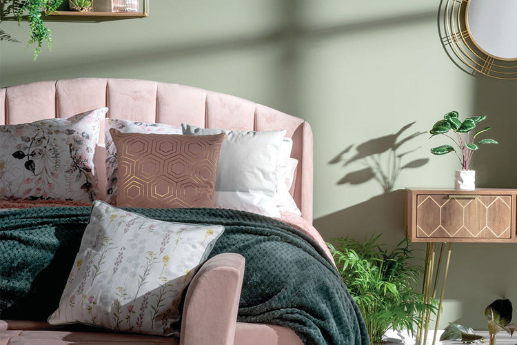 A pink bed illuminated by soft light filtering through a window