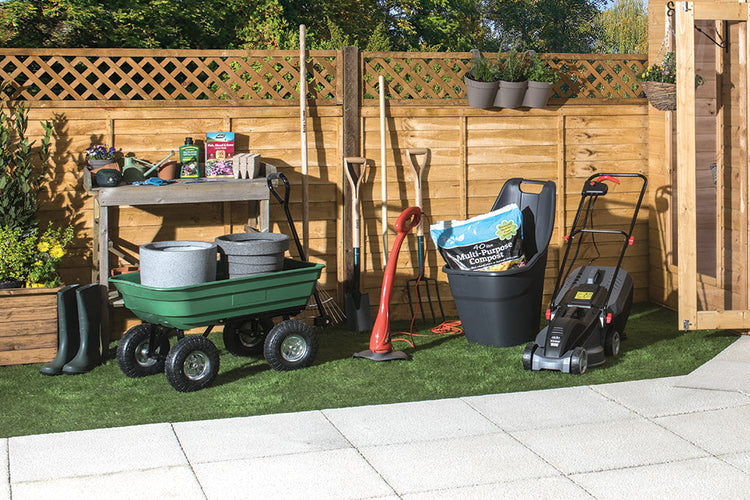 Various gardening equipment including lawnmowers and strimmers neatly arranged on grass