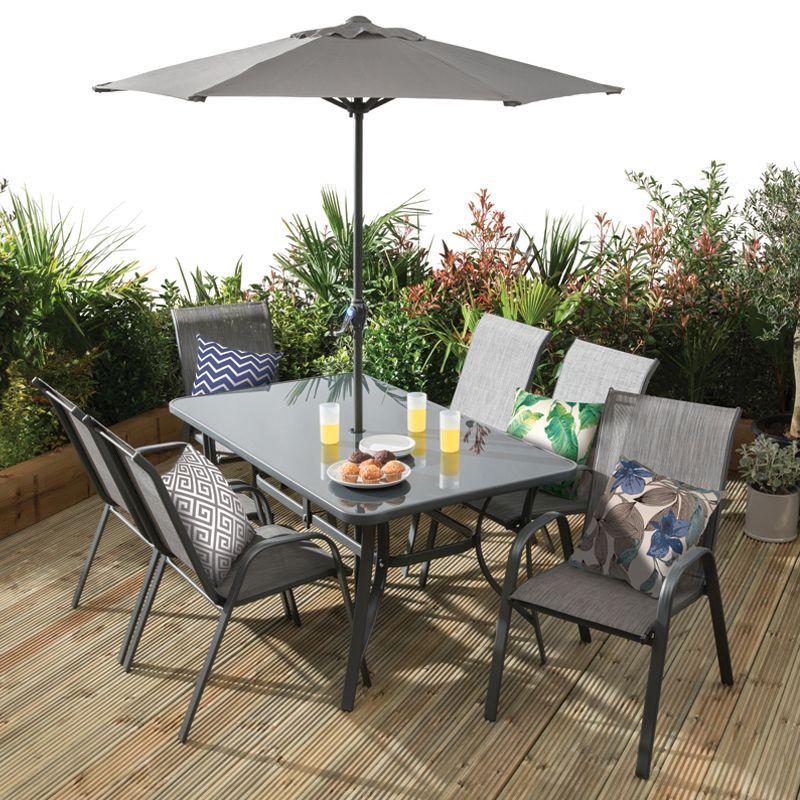 wo wooden chairs paired with a matching table, set on a patio outdoors surrounded by green plants