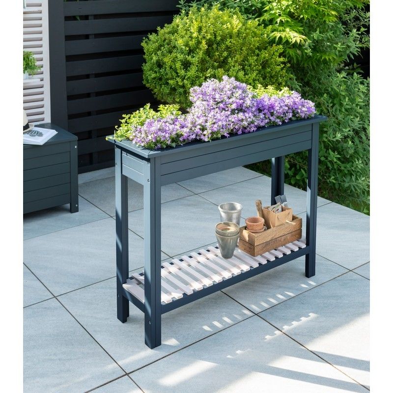 Two tier dark blue wooden raised planter with purple flowers, outside on a sunny day