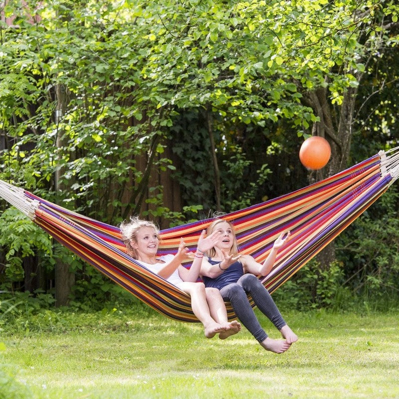 Two children happily sitting side by side on a red striped hammock