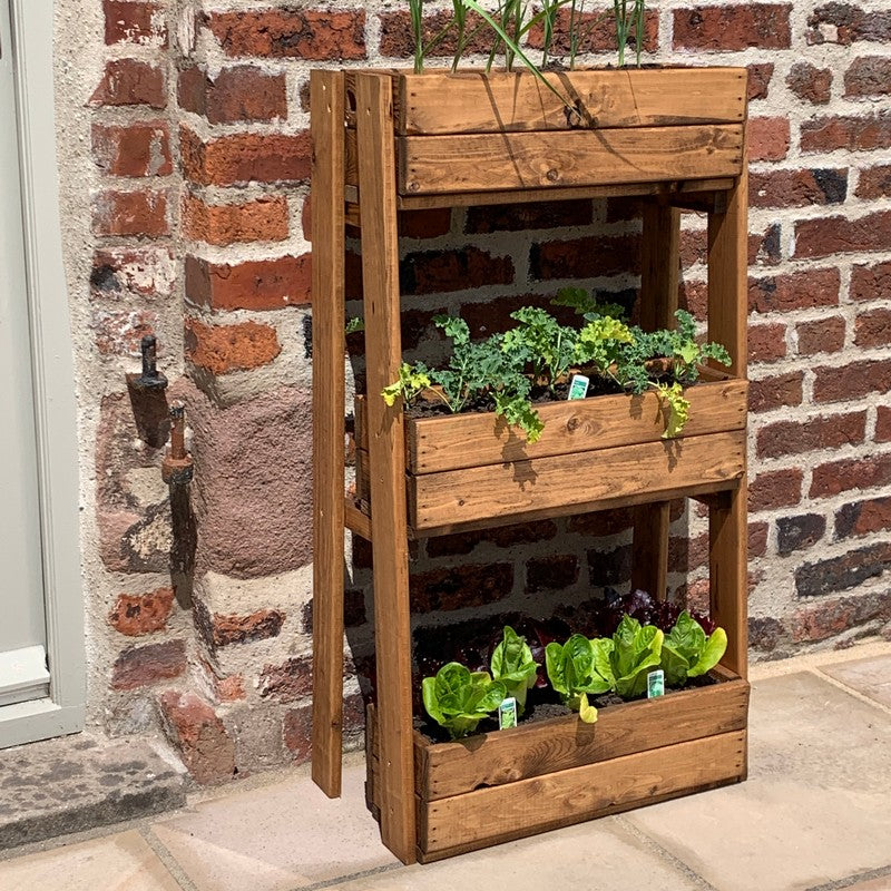 A three-tier wooden planter filled with lush green plants, arranged on a sunny patio, adding a touch of nature to the outdoor space