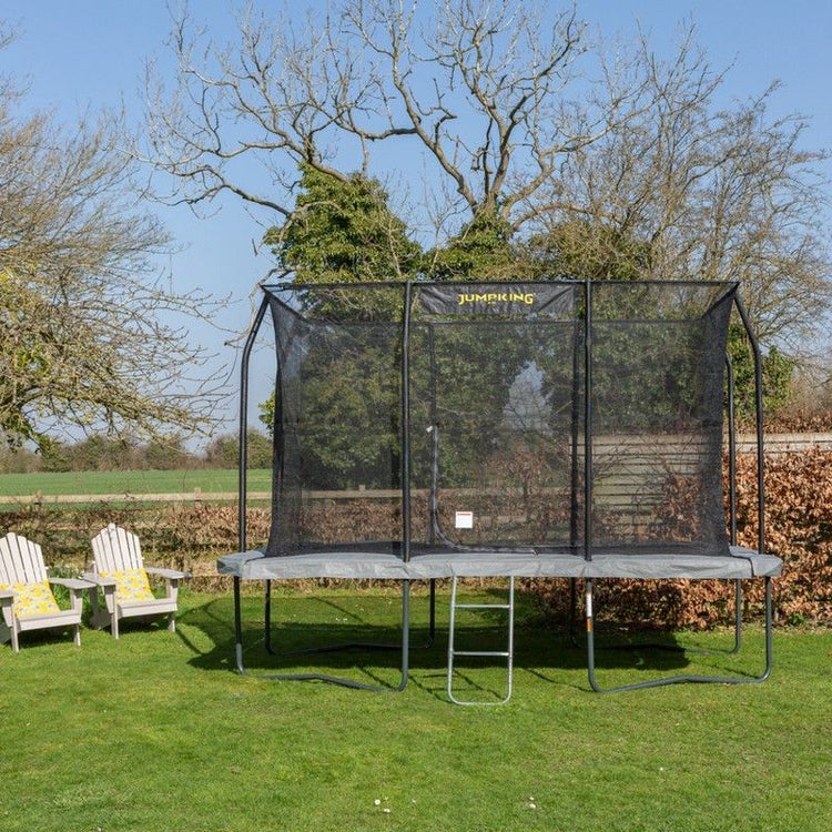 Small child jumping on a large fenced trampoline