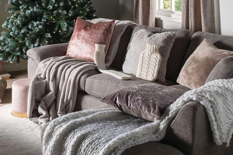  A grey sofa adorned with an array of cushions and throws