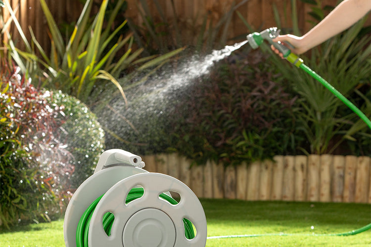 A person watering the grass with a hose, diligently tending to the lush green lawn on a sunny day.