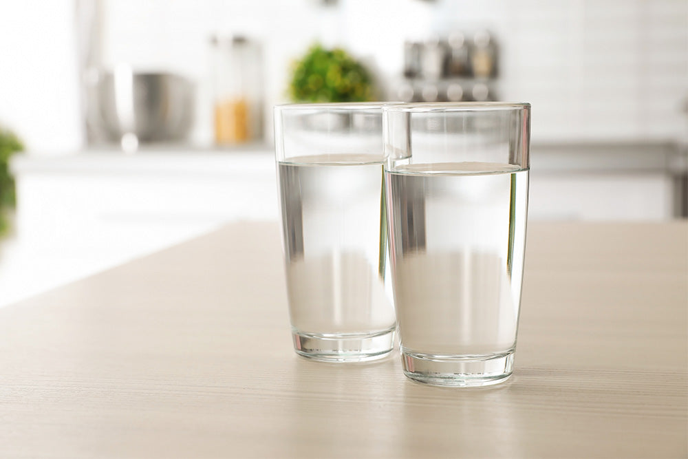 Two glasses of water placed on a kitchen table