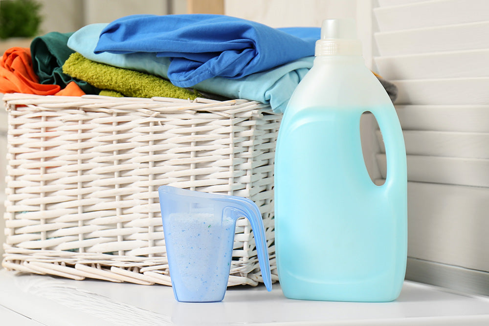 A basket of clothes beside washing detergent products