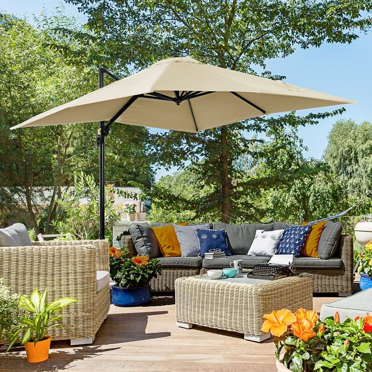 Cream overhand parasol , next to rattan garden furniture on a sunny day