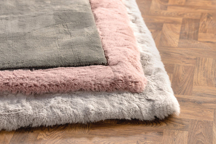 Three different sized rugs, ranging from small to large in the colours, grey, pink and white