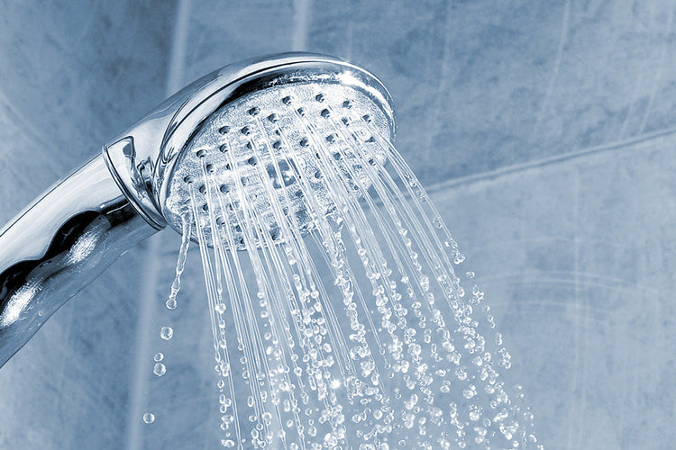 A silver running shower head in a bathroom