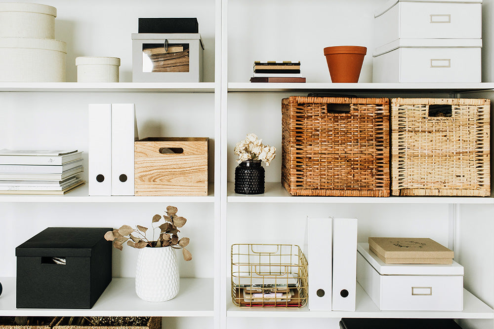 Large white bookshelf holding baskets and flower pots