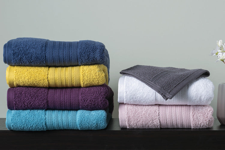 Range of coloured towels folded neatly on a sideboard